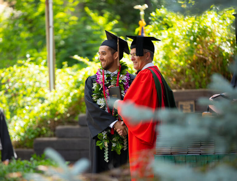 Male graduate receives diploma and shakes President McVay's hand.