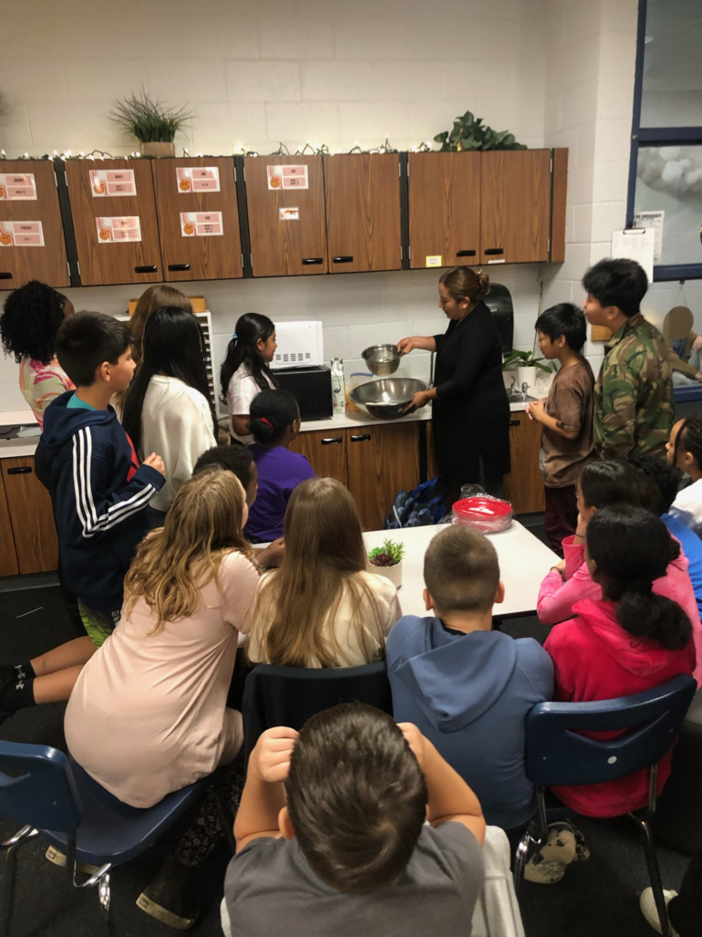 students crowd around teacher to see torillas being made