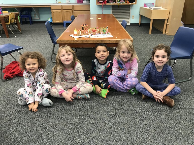 children sitting on the floor of a classroom smiling at the camera