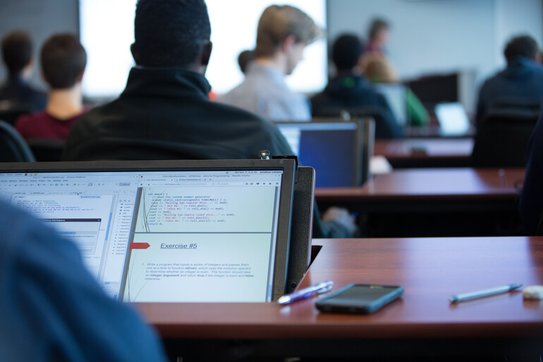 Students study at computer screen built into desks.