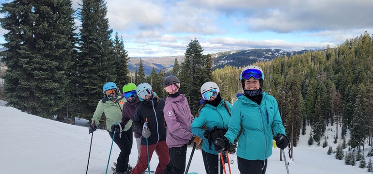 Group of skiing students smile at the top of a mountain