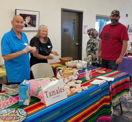 Smiling people serving vegetarian Mexican food.