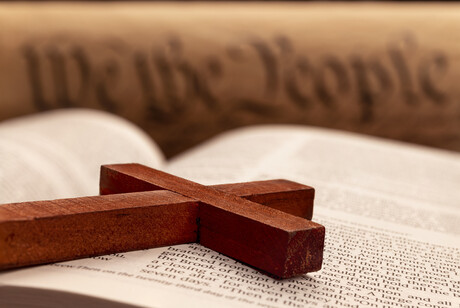 A wooden cross lays across a Bible.
