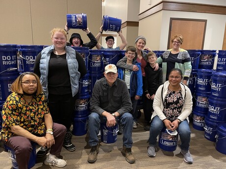 Volunteers take a photo next to buckets that are filled with supplies for flood victims. 