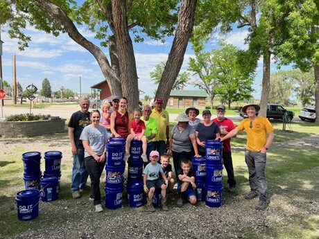 Volunteers take a photo next to buckets that are filled with supplies for flood victims.