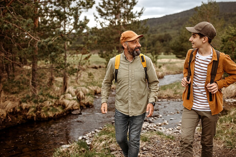 Father and son talking while walking by the river.