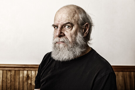 Grumpy, angry old bearded senior adult man curmudgeon frowning and staring sidelong at the camera.