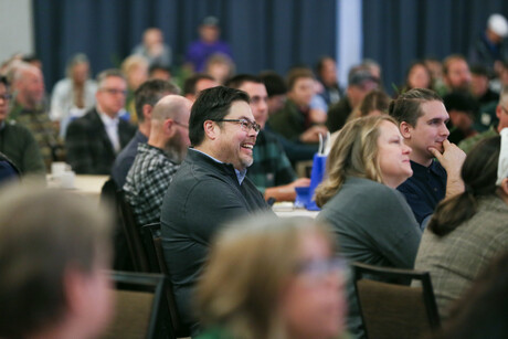 man smiles at something surrounded by a crowd of people