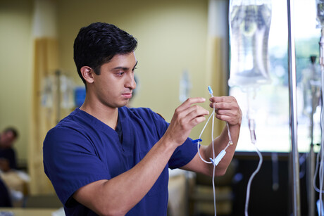 Male nursing student checks IV needle