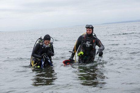 Scuba divers walk from ocean