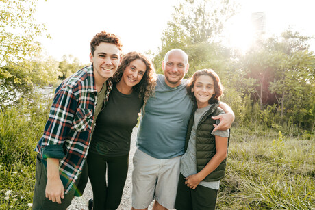 Family bonding and having a fun time together. Siblings and parents embracing and smiling at the camera.
