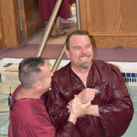 Man smiles while being baptized.
