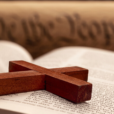 A wooden cross lays across a Bible.