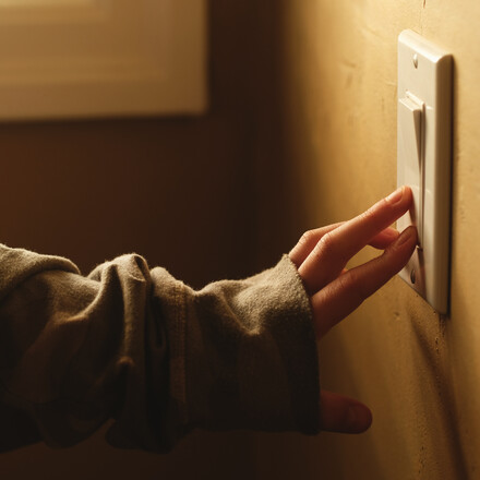 Hand turning on light switch.