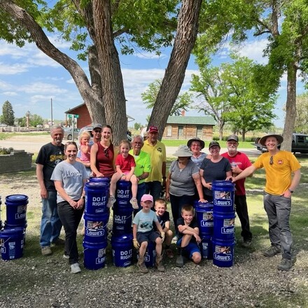 Volunteers take a photo next to buckets that are filled with supplies for flood victims.
