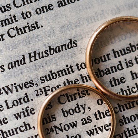 Closeup of two golden wedding rings and opened pages of holy bible represents the concept of marriage and the love between two Christians
