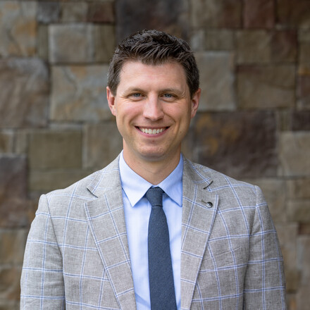 man looking at viewer in front of rock wall