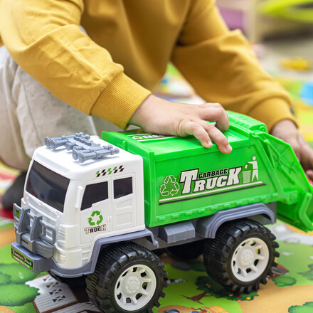 Child boy playing with a garbage truck toy on room floor at home - kid hands playing educational vehicle for learning sustainability and recycling. Toddler being creative and curious