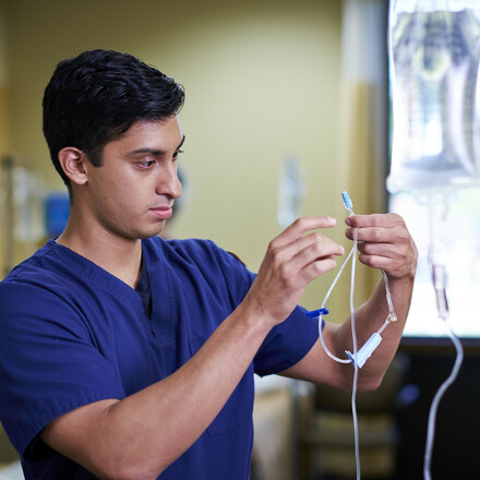 Male nursing student checks IV needle