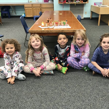 children sitting on the floor of a classroom smiling at the camera