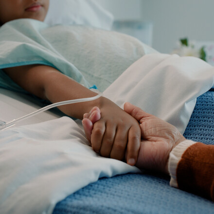 Hospital scene with an adult holding a child's hand