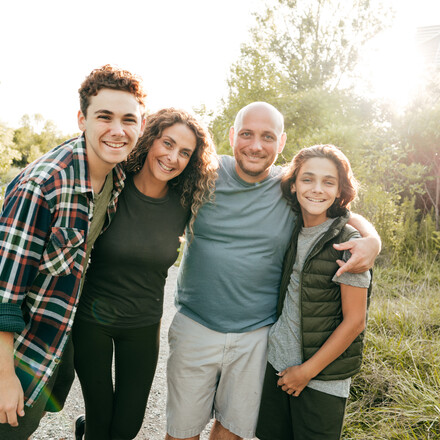 Family bonding and having a fun time together. Siblings and parents embracing and smiling at the camera.