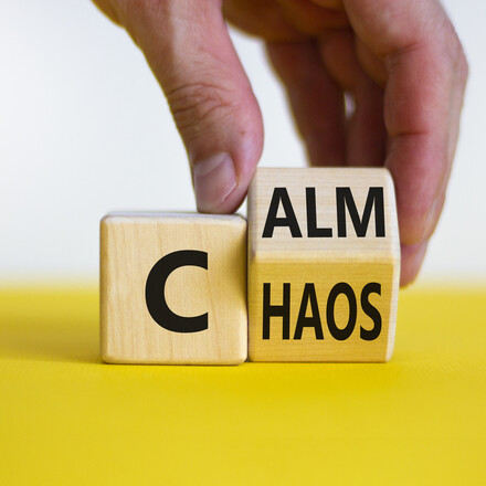 Stop chaos, time to calm. Male hand turns a wooden cube and changes the word 'chaos' to 'calm'.