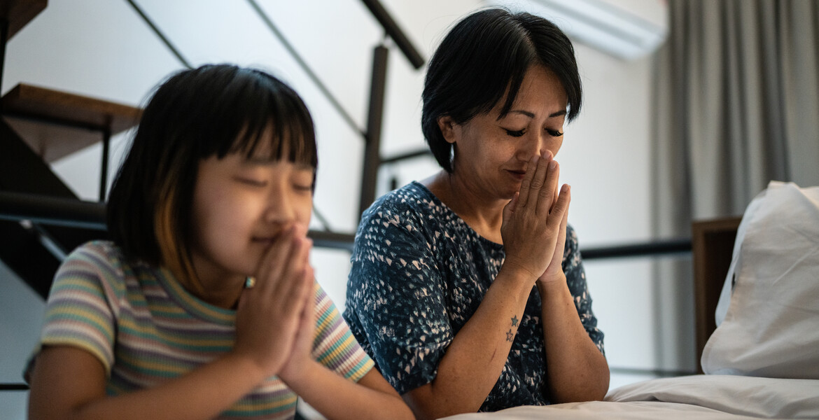 Mother and daughter praying at home