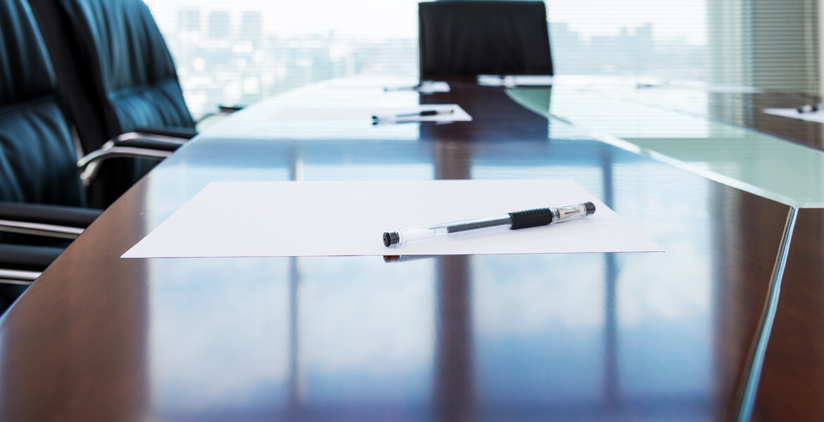 Corporate boardroom with blank paper set for the meeting.