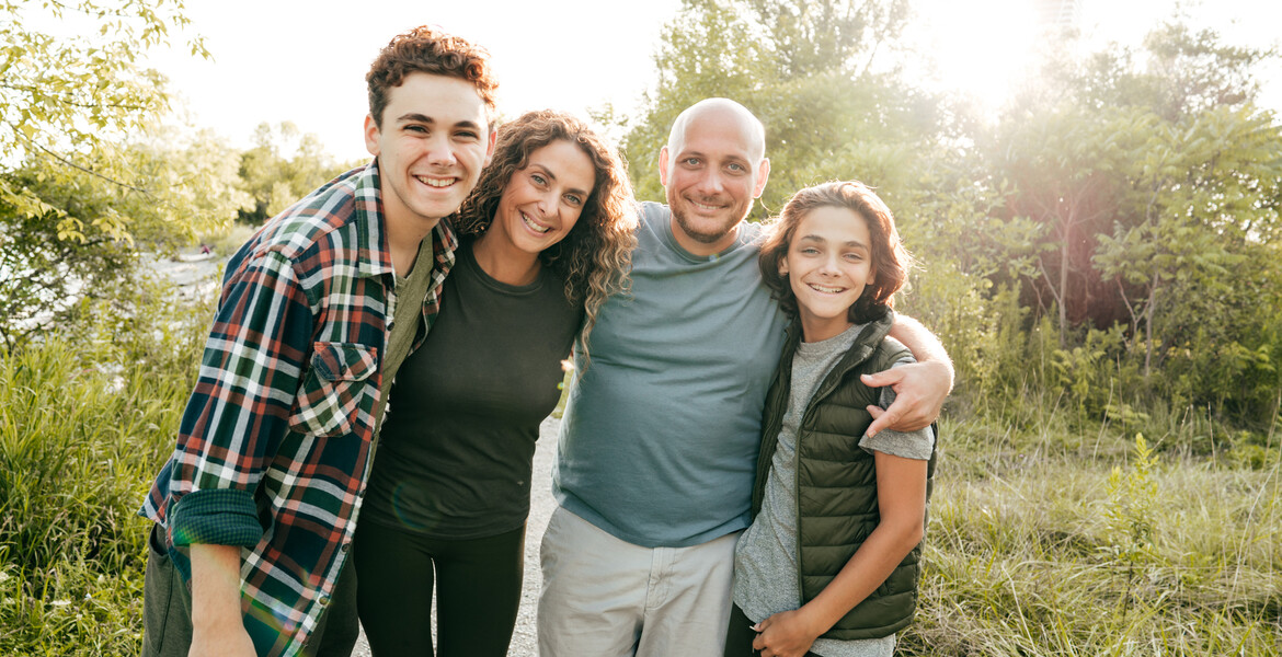 Family bonding and having a fun time together. Siblings and parents embracing and smiling at the camera.