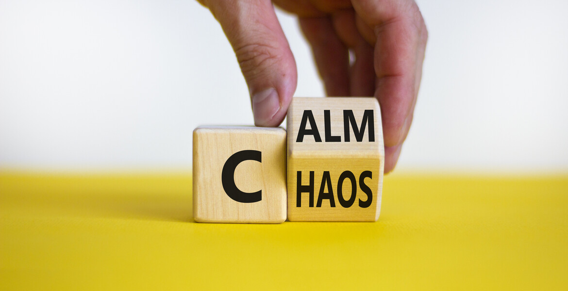 Stop chaos, time to calm. Male hand turns a wooden cube and changes the word 'chaos' to 'calm'.